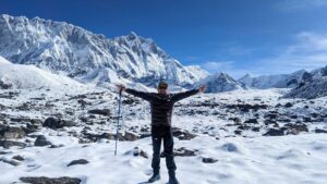 Dr. Timilsina hiking in a snowy terrain, Island peak in the background